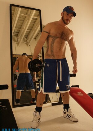 Strong hairy gay athlete Aitor Crash strips naked while lifting weights