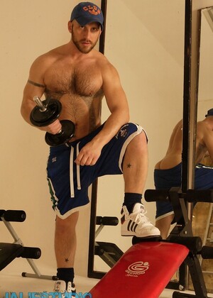 Strong hairy gay athlete Aitor Crash strips naked while lifting weights